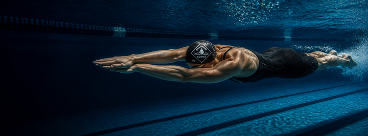 Swimmer wearing a CutWave silicone swim cap pulled snug over the head, gliding through pool water.