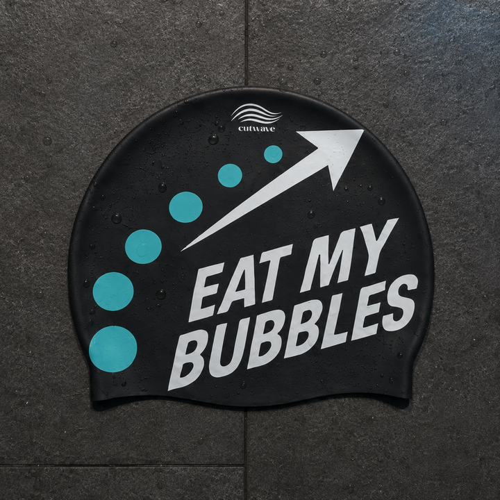 Eat My Bubbles black swim cap with teal bubbles and a white arrow.
