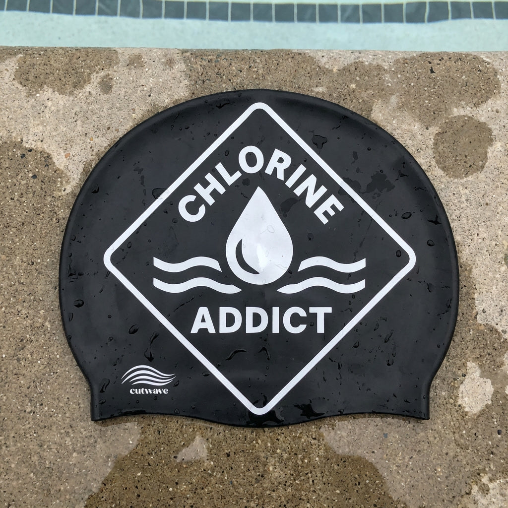 Chlorine Addict water drop design silicone swim cap by Cutwave on poolside surface