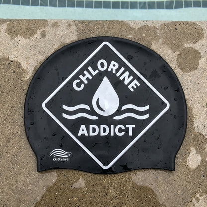 Chlorine Addict water drop design silicone swim cap by Cutwave on poolside surface